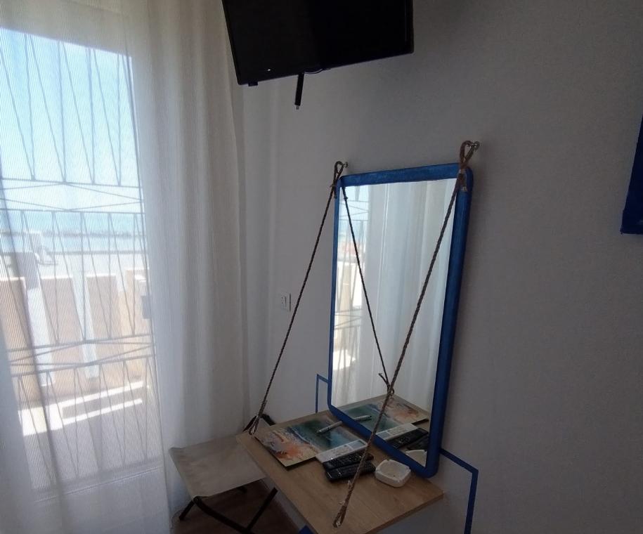 Camera con specchio sospeso e TV a parete.