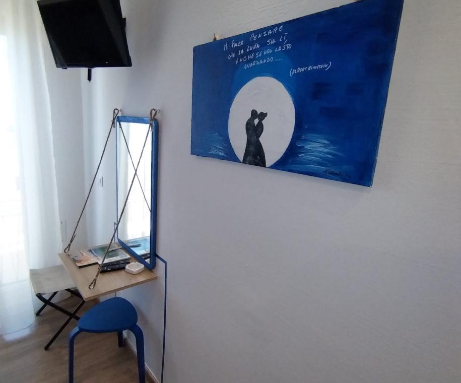 Stanza luminosa con quadro blu e scrivania.
