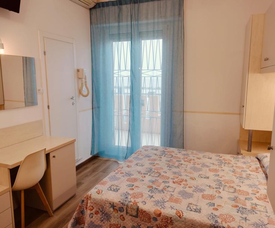Camera accogliente con letto matrimoniale e scrivania.