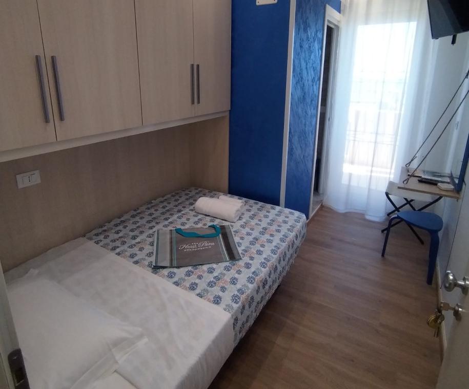 Camera singola con letto, armadio, scrivania e TV.