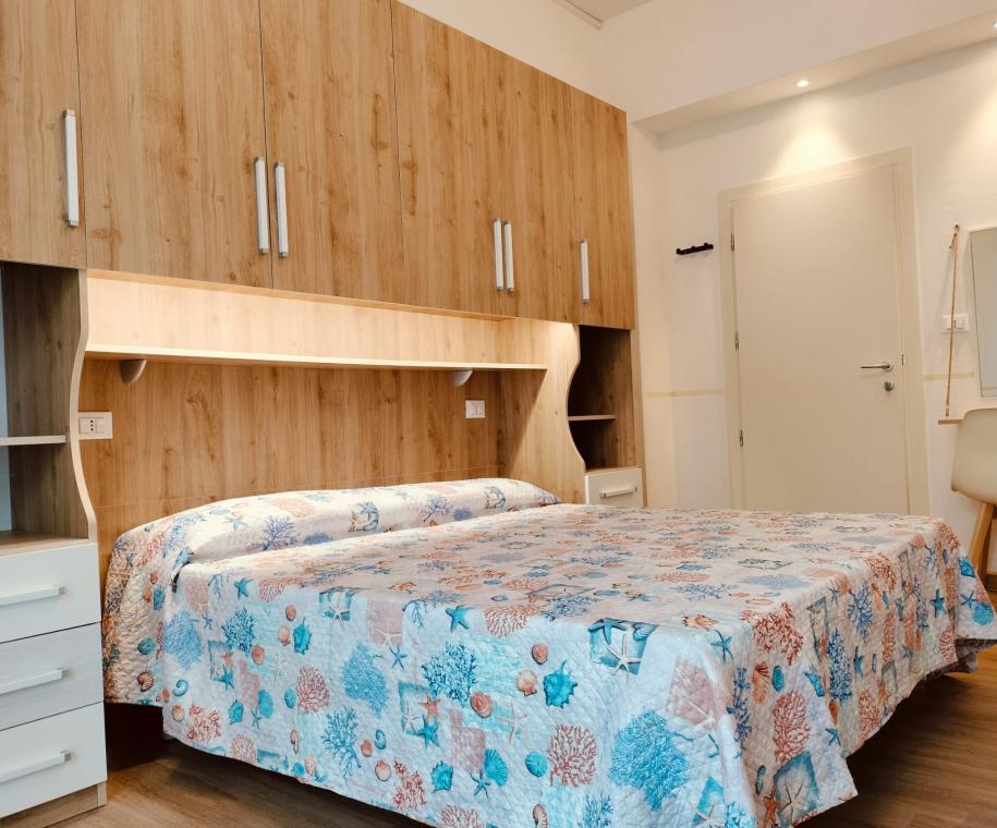Camera da letto con armadio e copriletto colorato a tema marino.