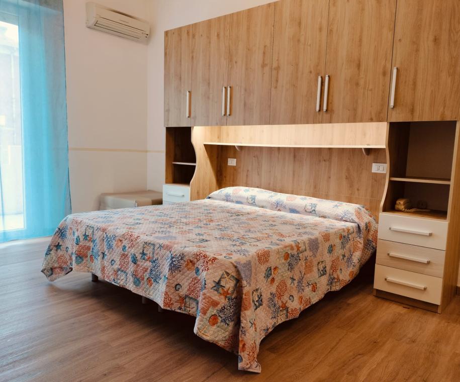 Camera da letto con armadio a ponte e copriletto colorato.