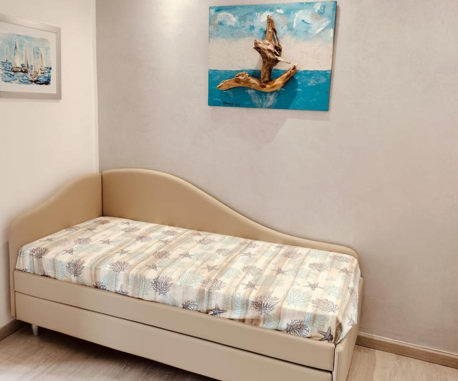 Camera moderna con letto singolo e quadri artistici alle pareti.